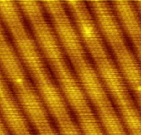 Um padrão de linhas diagonais nas cores dourado e marrom representando átomos de ouro, conforme observado com um microscópio eletrônico de tunelamento de varredura.