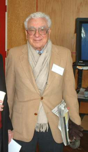 A imagem mostra uma foto do físico Murray Gell Mann, que parece um simpático cavalheiro de cabelos brancos.