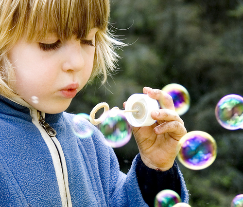 As bolhas de sabão que a criança sopra no ar mantêm sua forma devido à força atrativa entre as moléculas da bolha de sabão.