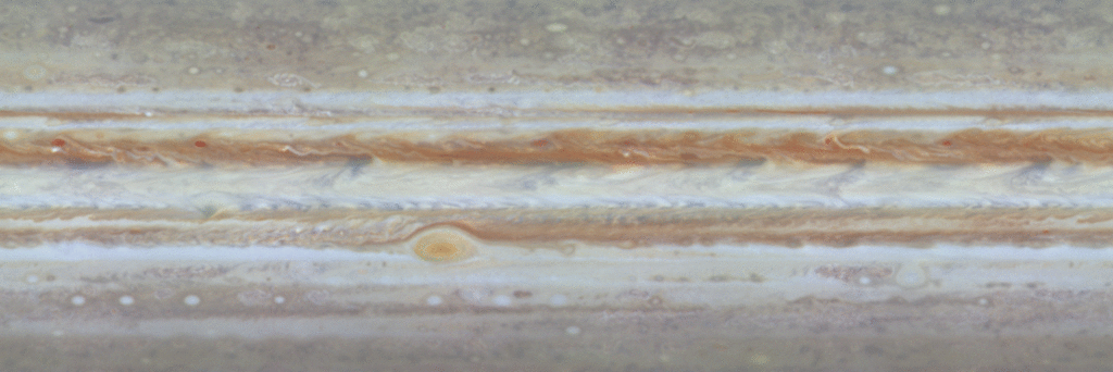 Various patterns of motion are apparent all across Jupiter at the cloudtop level seen here. The Great Red Spot shows its counterclockwise rotation, and the uneven distribution of its high haze is obvious. To the east (right) of the Red Spot, oval storms, like ball bearings, roll over and pass each other. Horizontal bands adjacent to each other move at different rates.