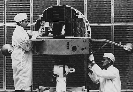 Two technicians work on the Orbiting Solar Observatory.
