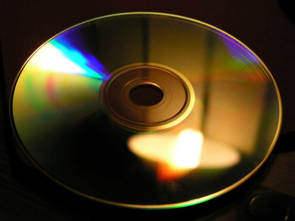 The bottom of a CD is shown with colors illuminated by a light reflection.