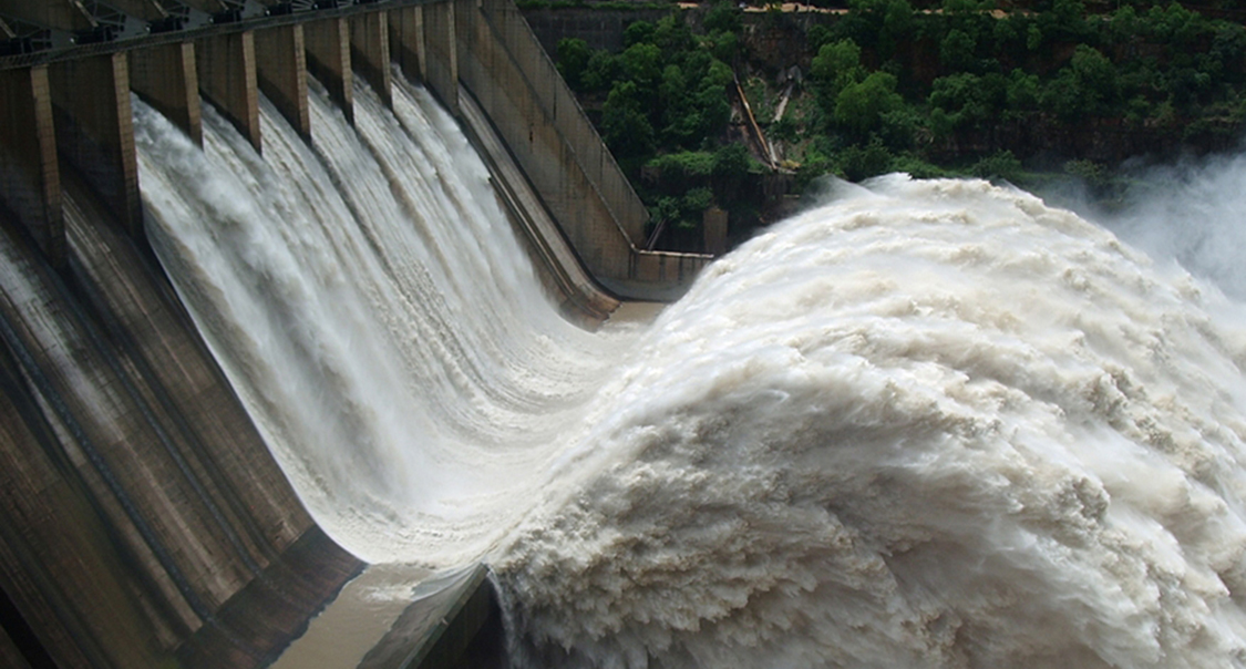 Um grande volume de água jorra dos portões de uma barragem em uma usina hidrelétrica.