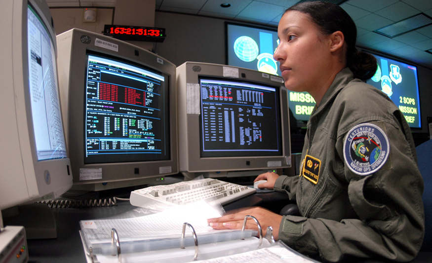 Fotografia de um operador de sistemas espaciais usando vários monitores de computador mostrando vários dados.