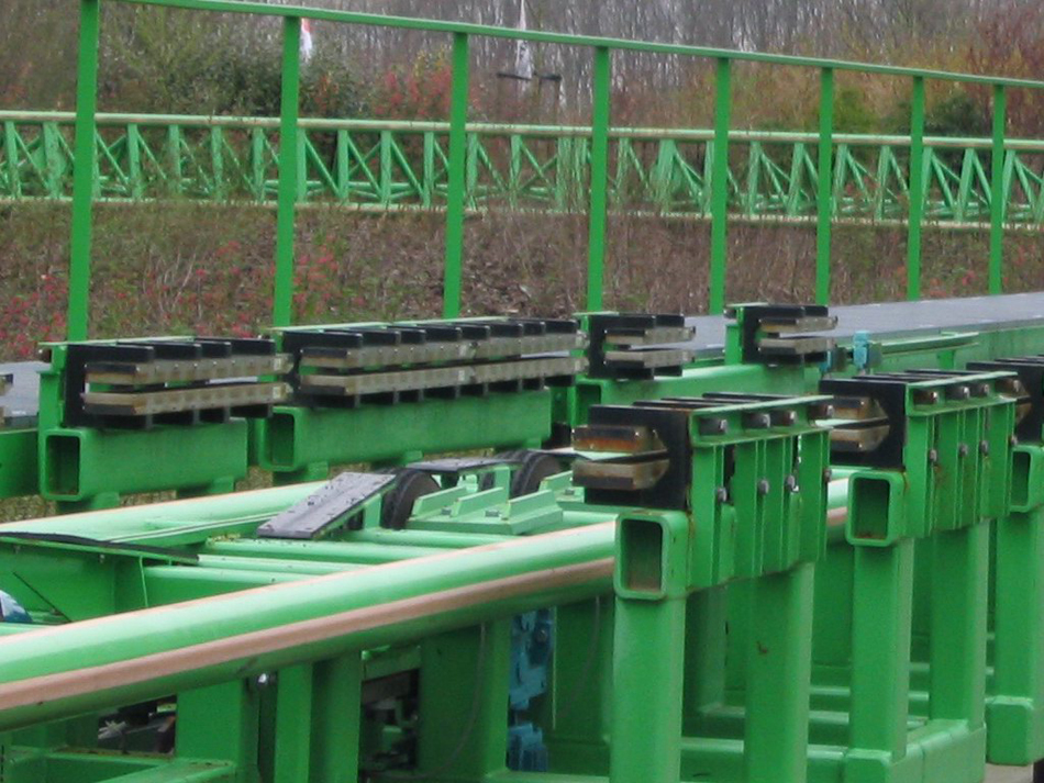Fotografia de uma pista de montanha-russa com fileiras de ímãs projetando-se horizontalmente que são usados para frenagem magnética em montanhas-russas.