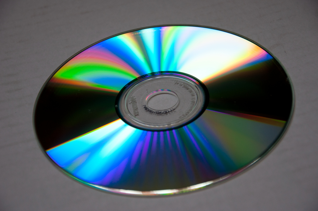 Fotografia do lado reflexivo de um CD. As regiões do disco refletem um arco-íris de cores.