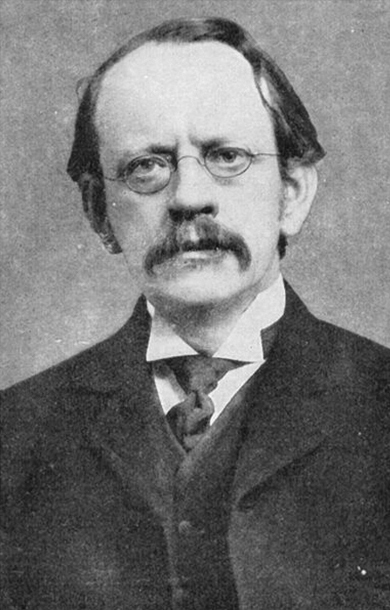 Uma imagem em preto e branco do cientista J. J. Thomson vestindo um casaco e óculos ovais.