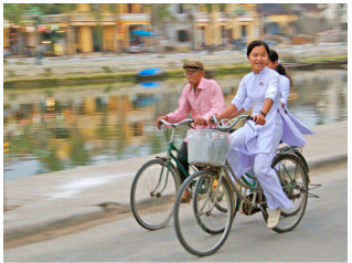 A imagem mostra três pessoas andando de bicicleta ao lado de um canal.
