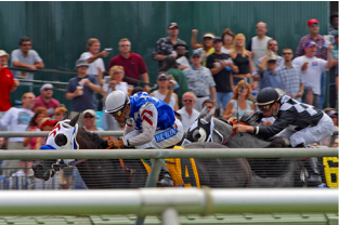 A imagem mostra dois cavalos de corrida com cavaleiros acelerando para fora do portão.