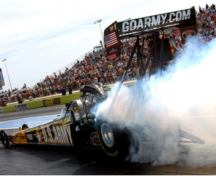 Picture shows a race car with smoke coming off of its back tires.