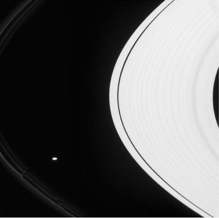 Image of Black and white image showing spatial relationship of barely visible F ring, Saturn’s oblong Prometheus satellite, and Saturn’s rings.