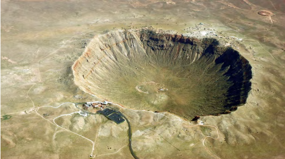 Uma foto da cratera do meteoro do Arizona. Os edifícios próximos à cratera são pequenos em comparação com a cratera.