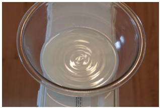 Photograph shows waves on the surface of a bowl of milk sitting on a box fan.