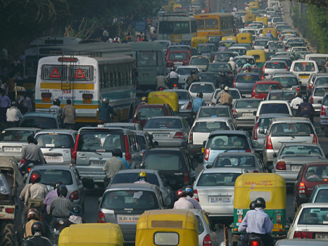 照片显示德里有一条挤满汽车和摩托车的道路。