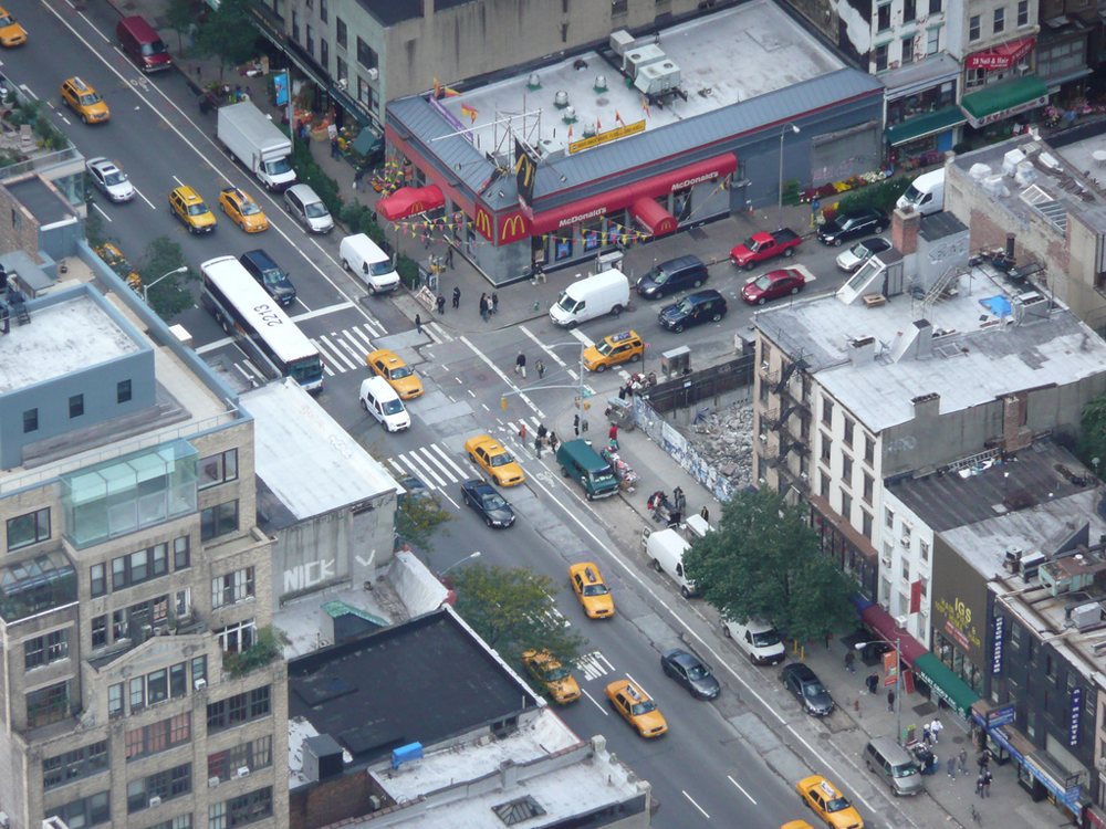 Um cruzamento de tráfego movimentado em Nova York mostrando veículos em movimento na estrada.