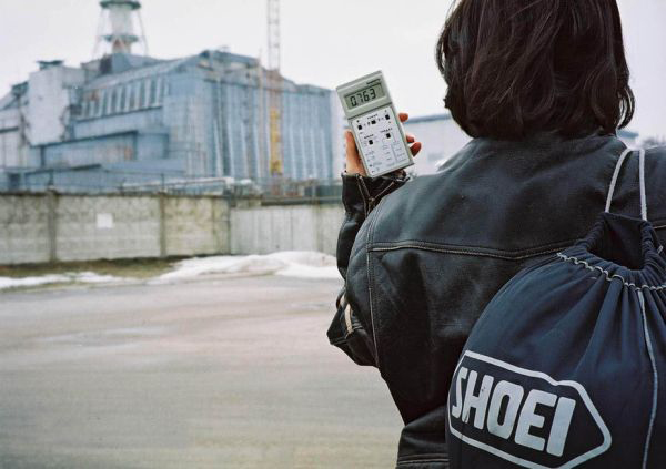 Uma pessoa segurando um detector de radiação portátil perto do reator de Chernobyl.