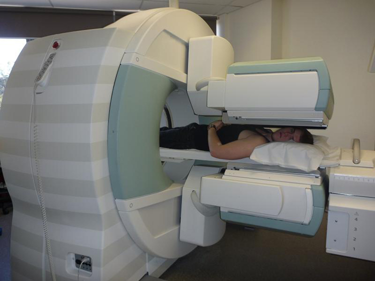 A man lying down, going through a cylindrical scanning machine.