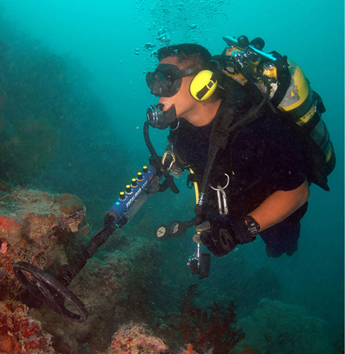 Photographie d'un plongeur sous-marin utilisant un détecteur de métaux.