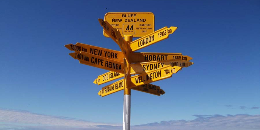 A photograph of a signpost with distances to numerous locations in different directions.