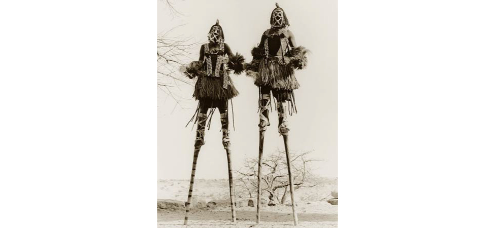 Picture shows a photograph of two stilt walkers in standing position.
