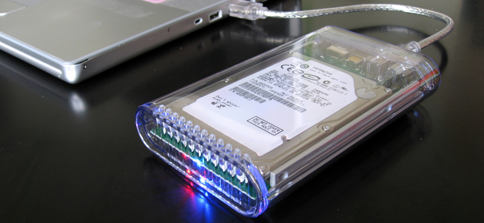 La photo montre un disque dur externe connecté à un ordinateur portable par un câble USB.